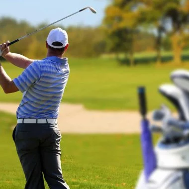 Man playing golf with golf bag