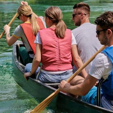 Group adventurous explorer friends are canoeing in a wild river surrounded by the beautiful nature