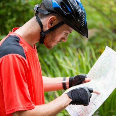 Male cyclist looking at map in countryside