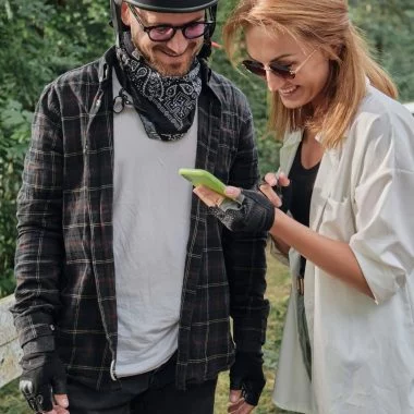 Middle age couple in helmet using mobile phone outdoors, travel together.